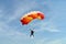 Parachuter, skydiver jumping and skydiving with red orange yellow colours parachute on parachuting competition, extreme sport