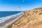 Parachuters flying over scenic beach against blue sky in San Diego California