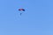 Parachutist descending with a parachute against blue sky