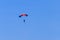 Parachutist descending with a parachute against blue sky