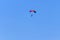 Parachutist descending with parachute against blue sky