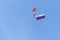 The parachutist descends from the sky with a state symbol, against the blue sky.