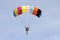 The parachutist goes down on a multi-colored parachute.