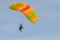 The parachutist goes down on a multi-colored parachute.