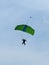 Parachutist with Green Parachute against Clear Blue Sky