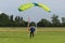 Parachutist with Green Parachute near to the Ground Preparing for Landing