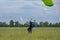 Parachutist with Green Parachute near to the Ground Preparing for Landing