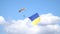 A parachutist with a huge flag of Ukraine descends on a yellow orange parachute