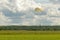 Parachutist lands in a field of grass