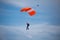 Parachutist with Orange Parachute against Clear Blue Sky