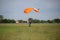 Parachutist with Orange Parachute near to the Ground Preparing for Landing