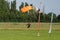 Parachutist with Orange Parachute near to the Ground Preparing for Landing