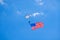 Parachutist seen against a deep blue sky trailing a large american flag