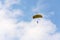 Parachutist skydiving with open yellow parachute clouds blue sky background