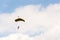 Parachutist skydiving with open yellow parachute clouds blue sky background