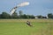 Parachutist with White Parachute near to the Ground Preparing for Landing.