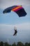 Parachutists: Instructor and Beginner with Blue Parachute against Clear Blue Sky