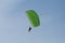 Parachutists: Instructor and Beginner with Green Parachute against Clear Blue Sky