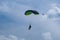 Parachutists: Instructor and Beginner with Green Parachute against Clear Blue Sky