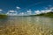 Paradise beach on a large lake with crystal clear shallow coastal water and a sandy bottom under a blue sky. summer holiday