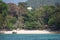 Paradise beach surrounded by large trees with some bungalows and turquoise