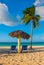 Paradise landscape. Umbrella and two lounge chairs around palm trees. Tropical beach. Caribbean sea, Holguin, Cuba, Playa Esmerald