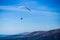 Paraglide silhouette flying over Carpathian peaks mountains on blue sky background.