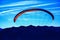 Paraglider above blue mounatins and sky