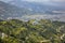 Paraglider on a blue parachute flies in a green mountain valley with the city of Pokhara