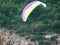 Paraglider flew over the trees and rocky cliff. colorful bright parachute on the background of green trees