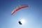 A paraglider flies a glider against a blue sky in good sunny weather. Close up