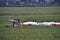 The paraglider after the flight stands on the green grass in the field, the dome and wing are lowered to the ground