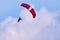 Paraglider flying against a partially cloudy sky.