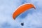 Paraglider flying orange wing