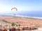 Paraglider flying over an arid coastal plain
