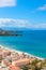 Paraglider flying over the beautiful blue bay in Italian Cefalu, Sicily captured on a vertical picture. Paragliding is a popular