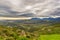 Paraglider flying over the green mountains around Cape Town, South Africa. Winter season, cloudy and dramatic sky. Unrecognizable