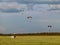Paraglider flying with a paramotor over a field of white flowers. The white car with balloons tied to chairs and tripods are props