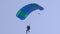 Paraglider is flying in sky leading canopy by straps, view on sportsman from ground, tilt up