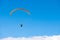Paraglider gliding over white clouds in the blue sky