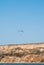 Paraglider hovering over the cliff and the landscape of the sea, soaring on the rising air, extreme and entertainment,