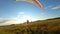 Paraglider lands on the green field against colourful sunset or sunrise