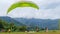 paraglider pilot with green parachute landing on field in Batu City, East Java, Indonesia on July 8, 2023