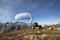 Paraglider pilot sits on a rock and balances his paraglider above his head near Lake Grimsel in the Swiss Alps