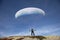 Paraglider Pilot stands on a slope and balances his paraglider above his head in the Alps of Switzerland