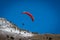 Paraglider With Red Parachute Wing Flying in a Blue Sky With Clouds