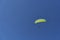 A paraglider sailing across a blue sky.