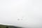 Paraglider silhouette flying in foggy sky in Carpathian mountains. Popular tourist extreme sport