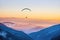 Paraglider silhouette flying over misty mountain valley in beautiful warm sunset colors - sport, active wallpapers full of freedom