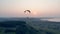 Paraglider in the sky. Airsailing vehicle is drifting above green landscape . Parachute, paragliding comcept.